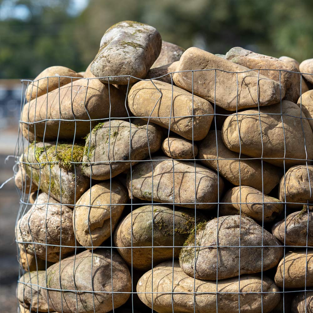 Stack of stones in a wire cage with a blurred natural background