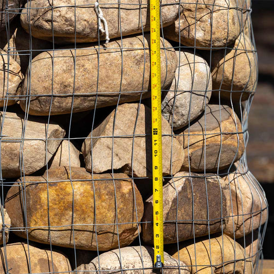Boulders in a wire cage with a tape measure for scale