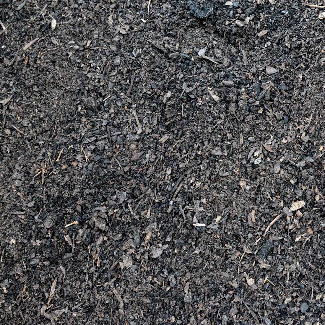 Dark brown and black mulch or compost material with visible wood chips, twigs, and organic debris, filling the frame.