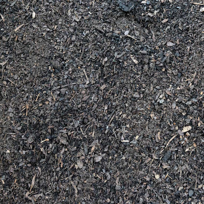 Dark brown and black mulch or compost material with visible wood chips, twigs, and organic debris, filling the frame.
