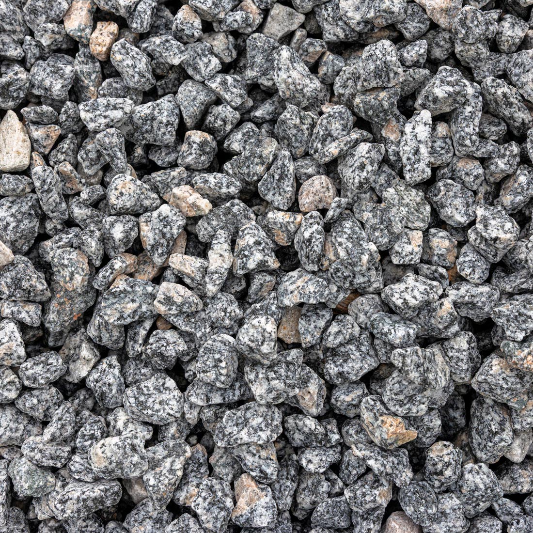 Gray and black granite decorative gravel stones with natural speckled patterns and a few light tan outliers, filling the entire frame.