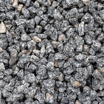 Gray and black granite decorative gravel stones with natural speckled patterns and a few light tan outliers, filling the entire frame.